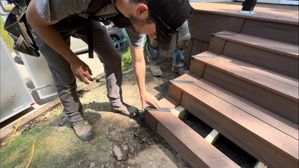 Two builders setting the framing for composite deck stairs on a job site